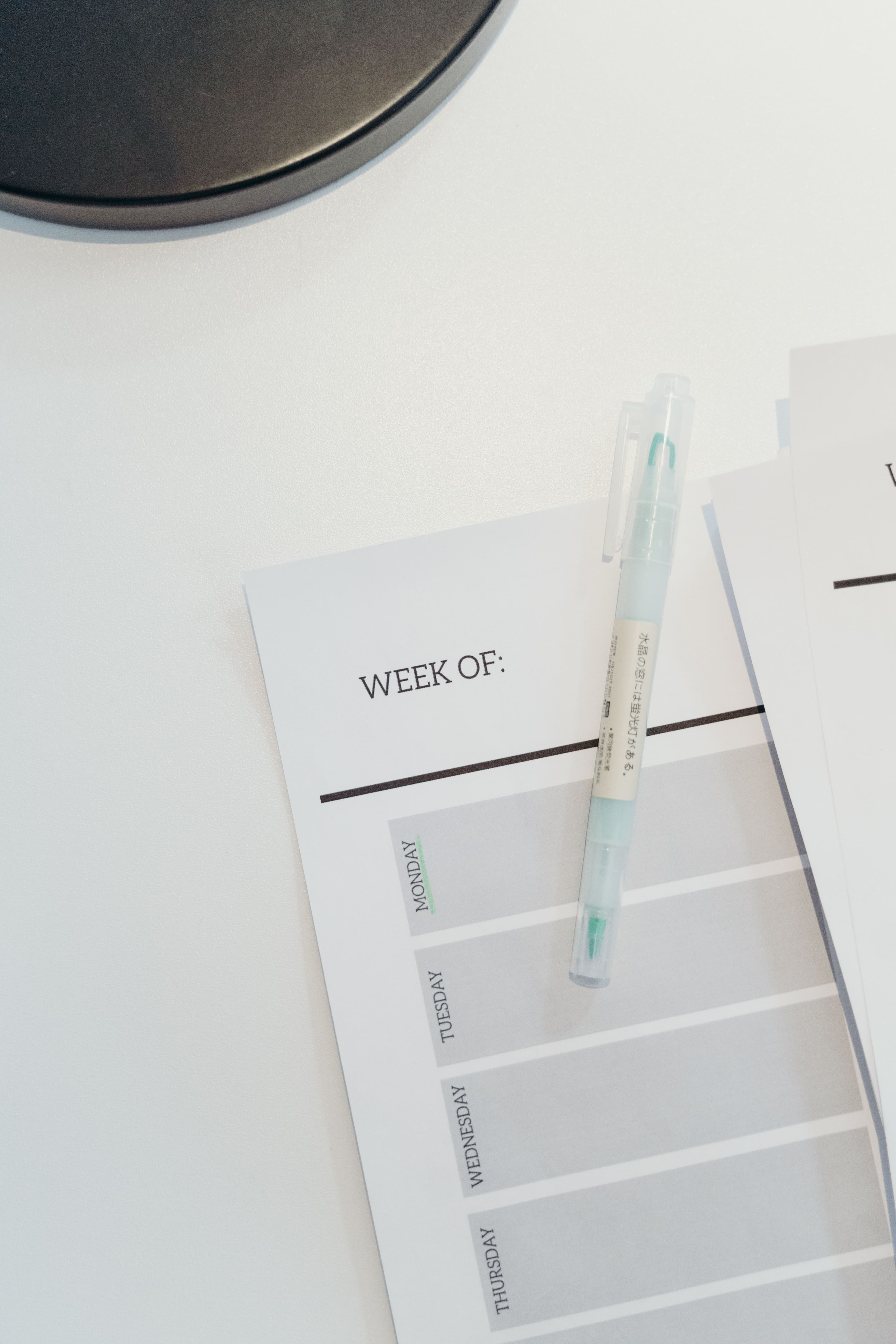 Light green highlighter on a weekly planner sheet resting on a white desk surface.